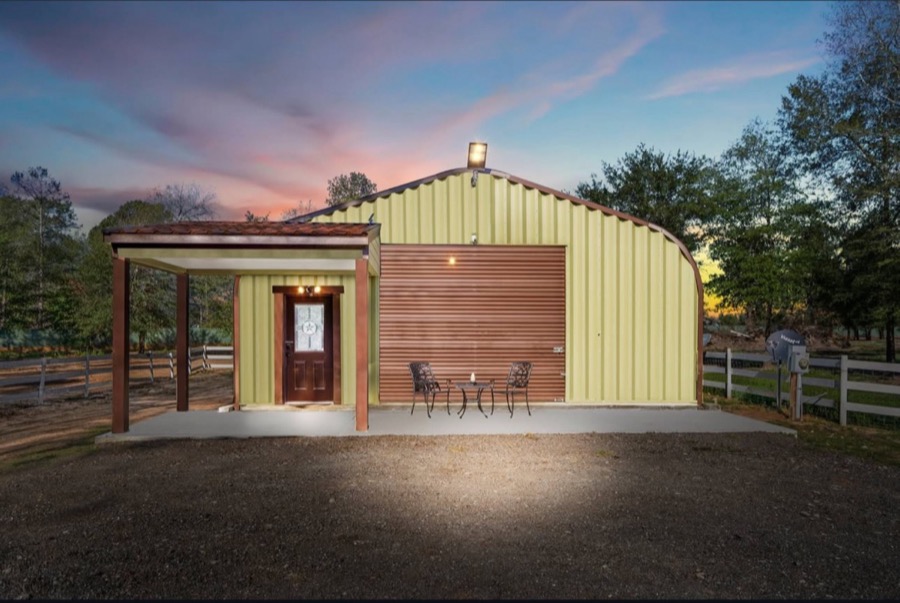 Inspira Ranch private barndominium building exterior at dusk with warm interior light and pink sky