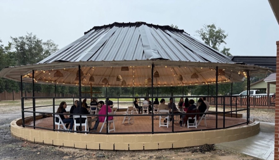 Inspira Ranch round outdoor gazebo with guests seated under rattan pendant lights